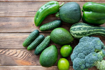 Fresh green vegetables and fruits on wooden table background, top view. Assortment of veg. Bright colors. 