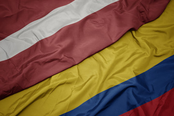 waving colorful flag of colombia and national flag of latvia.