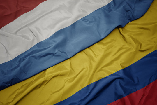 waving colorful flag of colombia and national flag of luxembourg.
