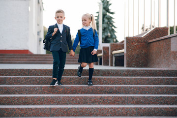 Little students go to school. Schoolchildren on background of flags of foreign countries.