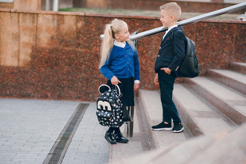 Little students go to school. Schoolchildren on background of flags of foreign countries.