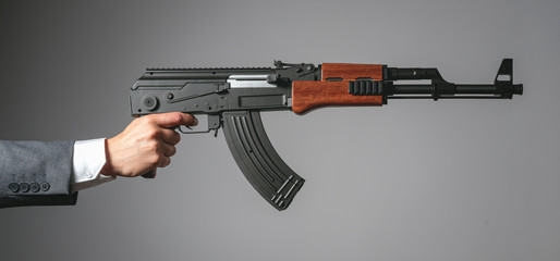 Hand with assault riffle isolated on a gray background.