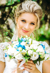 Fototapeta premium Tender bride with bouquet in hands on nature background