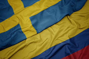 waving colorful flag of colombia and national flag of sweden.