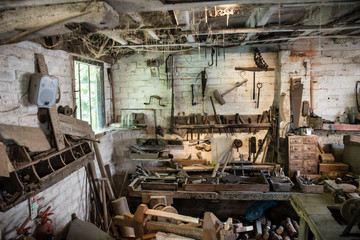 An abandoned workshop with dusty tools and cobwebs in front of a dirty window.