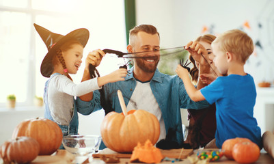 happy Halloween! family mother father and children cut pumpkin for holiday at home