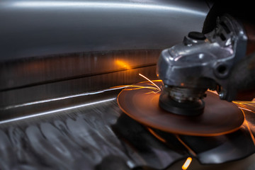 Worker cutting metal part using hand Angle Grinder Machine. Freeze motion sparks , close-up.