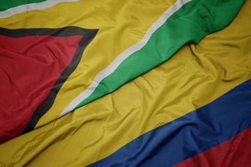 waving colorful flag of colombia and national flag of guyana.