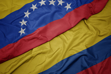 waving colorful flag of colombia and national flag of venezuela.