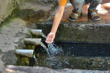 The child touches the water that flows from the spring
