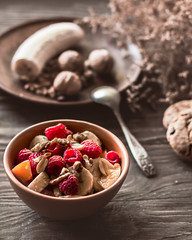 Fruit salad with nuts and cookies for breakfast. Healthy food, vegetarianism. Wooden background