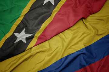 waving colorful flag of colombia and national flag of saint kitts and nevis.