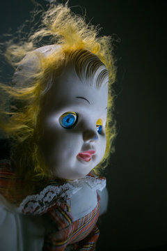 Scary old doll under dramatic light