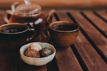 Handmade sweets from a small pastry shop with two cups and a teapot on a cozy wooden background. Copy space.