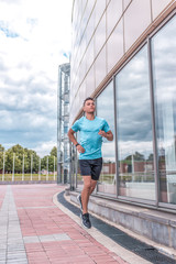 Athletic male athlete, in summer runs in city on jog in morning, motivation for doing fitness sports workout, in morning workout. Active lifestyle of young people, powerful and stylish man.