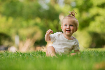 baby girl in a white sandpit on the green grass playing pyramid