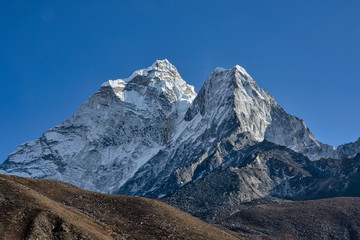 Brown and rocky hills lay in the foreground as huge snowcapped Himalayan mountains cover nearly the entire background