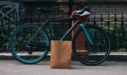 Bearded male courier with bicycle delivery food service at home. Shopping paper bag with copy space for your text or advertising content. No name shopping bag