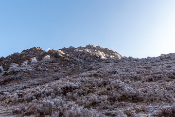 The morning frost spreads across the brown and dry hillside in Nepal on a clear and sunny day