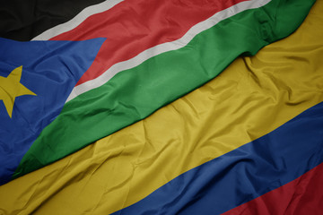 waving colorful flag of colombia and national flag of south sudan.