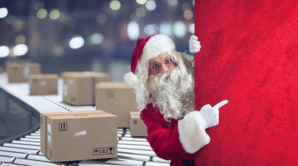 Santa Claus indicates a space for the Christimas present, with ready packages on background