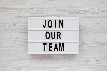 'Join our team' words on a modern board on a white wooden surface, top view. Overhead, from above,...