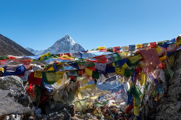 Mountain peak above prayer flags fluttering with the wind in the Himalayan mountains of Nepal