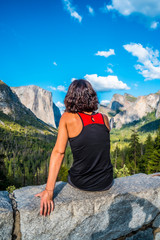 Naklejka premium A young woman in pink and black at the Tunnel View viewpoint, Yosemite National Park. United States