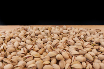 Shell pistachios on wooden table and black background
