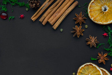 Merry Christmas and happy new year. composition on a black background of Christmas tree branches, cones, toys, cinnamon, dried oranges and anise. Greeting background, card or layout design. copy space