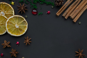 Merry Christmas and happy new year. composition on a black background of Christmas tree branches, cones, toys, cinnamon, dried oranges and anise. Greeting background, card or layout design. copy space