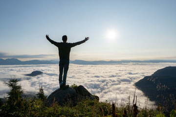 Fototapeta na wymiar hiker celebrating success on top of a mountain above the clouds. Young man enjoying freedome, Mountaineering sport lifestyle concept