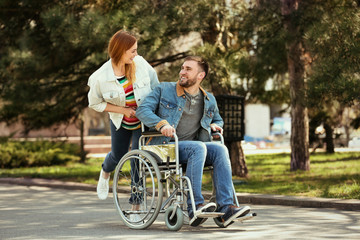 Obraz na płótnie Canvas Young man in wheelchair and joyful woman at park