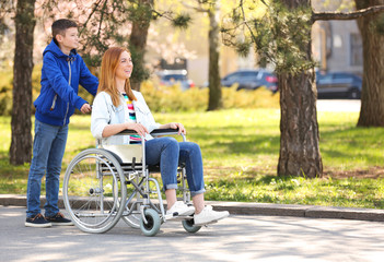 Woman in wheelchair and her son at park on sunny day