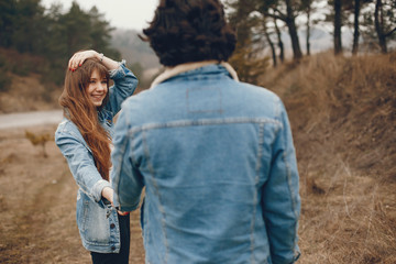 gentle and stylish couple are having a walk in the autumn park