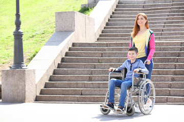 Preteen boy in wheelchair with his mother outdoors