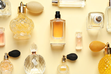 Flat lay composition with different perfume bottles on light yellow background