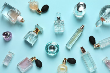 Flat lay composition with different perfume bottles on light blue background