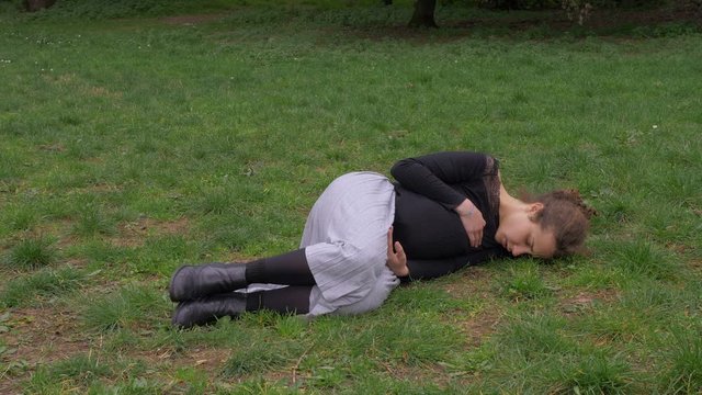 sick drug addict young woman lying alone on the grass. Illness, addiction