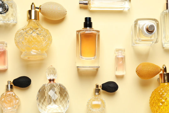 Flat lay composition with different perfume bottles on light yellow background
