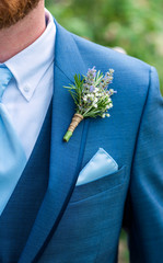 boutonniere made with lavender, rosemary, and babys breath tied with twine pinned to a blue jacket, blue tie, wedding day clothes