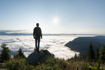Fototapeta na wymiar hiker standing on the top of a mountain and enjoying an amazing view over a cloud covered valley. Luck happiness and freedom concept in South Tyrol Italy