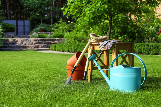 Set of gardening tools and stool on green grass