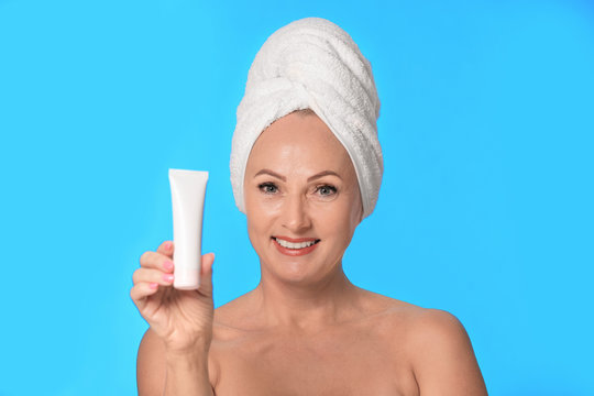 Foto Stock Portrait of beautiful mature woman with perfect skin holding tube  of cream on light blue background | Adobe Stock