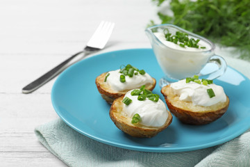 Delicious potato wedges with sour cream on white wooden table