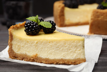 Piece of delicious cheesecake decorated with blackberries on table