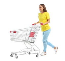 Young woman with empty shopping cart on white background