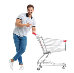 Young man with empty shopping cart on white background