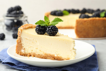Piece of delicious cheesecake with blackberries on table, closeup