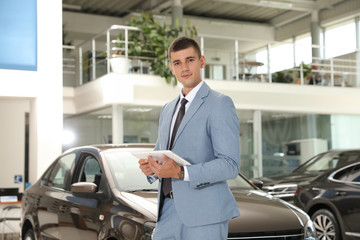 Fototapeta premium Young salesman with tablet in modern car dealership